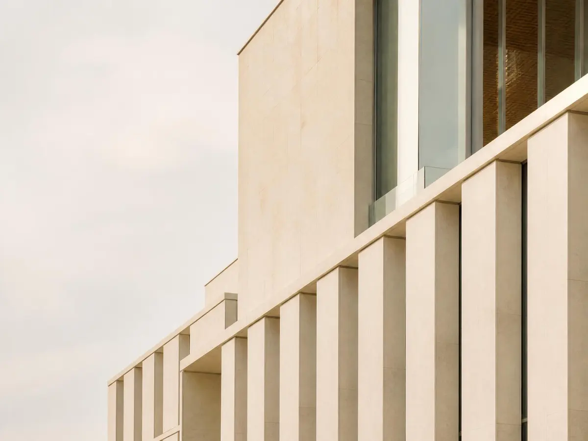 Detail of a limestone and glass institutional building facade in warm daylight